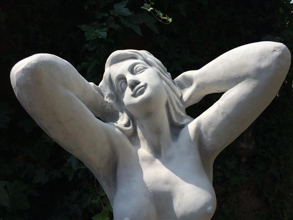 Grote foto mooi vol stenen beeld van een naakte knielende vrouw heel fraai tuin en terras tuindecoratie