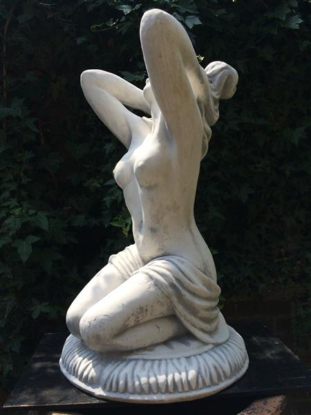 Grote foto mooi vol stenen beeld van een naakte knielende vrouw heel fraai tuin en terras tuindecoratie