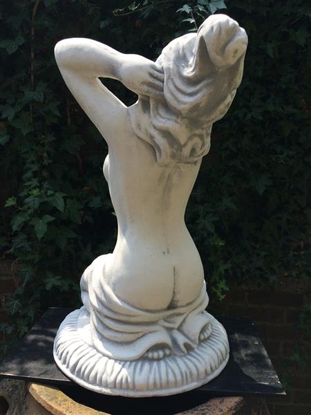 Grote foto mooi vol stenen beeld van een naakte knielende vrouw heel fraai tuin en terras tuindecoratie