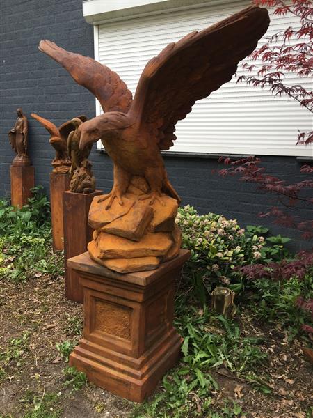 Grote foto zeer forse adelaar oxide steen in prooipakkende actie bruin op sokkel. tuin en terras tuindecoratie