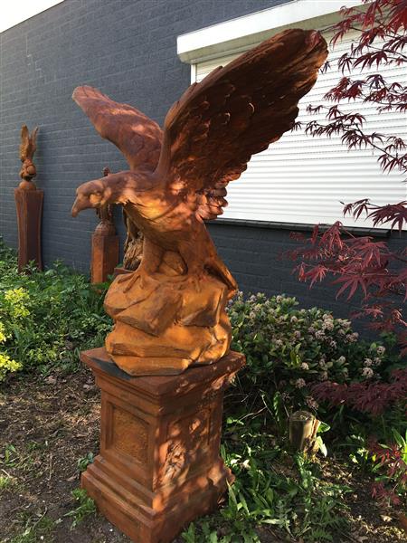 Grote foto zeer forse adelaar oxide steen in prooipakkende actie bruin op sokkel. tuin en terras tuindecoratie