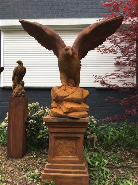 Grote foto zeer forse adelaar oxide steen in prooipakkende actie bruin op sokkel. tuin en terras tuindecoratie
