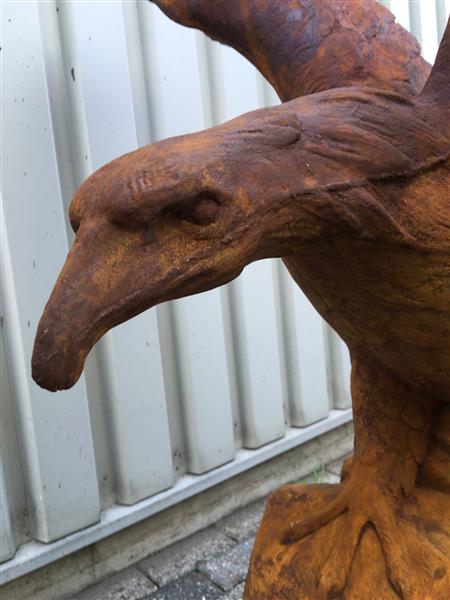 Grote foto zeer forse adelaar oxide steen in prooipakkende actie bruin op sokkel. tuin en terras tuindecoratie