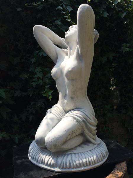 Grote foto mooi vol stenen beeld van een naakte knielende vrouw heel fraai tuin en terras tuindecoratie
