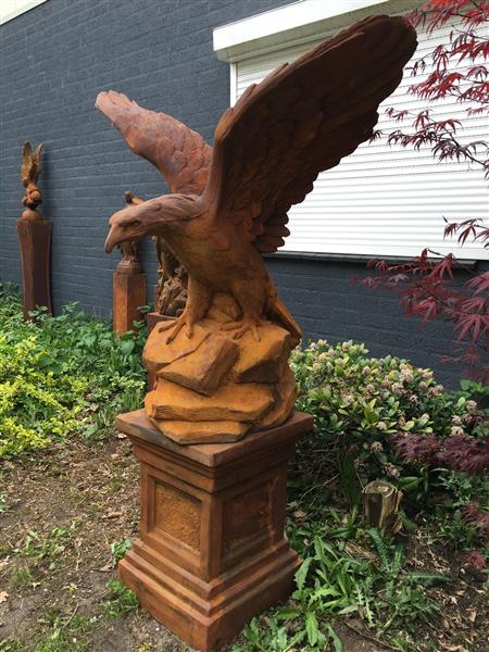 Grote foto zeer forse adelaar oxide steen in prooipakkende actie bruin op sokkel. tuin en terras tuindecoratie