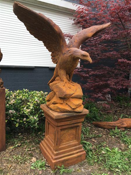 Grote foto zeer forse adelaar oxide steen in prooipakkende actie bruin op sokkel. tuin en terras tuindecoratie