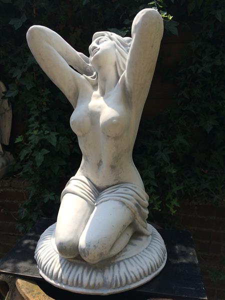 Grote foto mooi vol stenen beeld van een naakte knielende vrouw heel fraai tuin en terras tuindecoratie