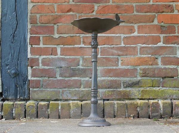 Grote foto fraai vogelbad op voet met leuk decoratief vogeltje op de rand van het bad gietijzer tuin en terras tuindecoratie