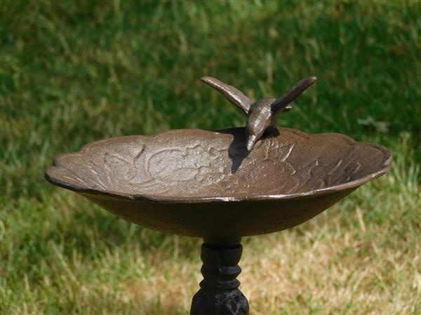 Grote foto fraai vogelbad op voet met leuk decoratief vogeltje op de rand van het bad gietijzer tuin en terras tuindecoratie