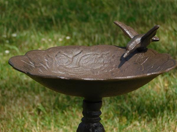 Grote foto fraai vogelbad op voet met leuk decoratief vogeltje op de rand van het bad gietijzer tuin en terras tuindecoratie