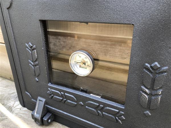 Grote foto ovendeur voor de kachel of oven temperatuur meter kachel is van gietijzer. tuin en terras tuindecoratie