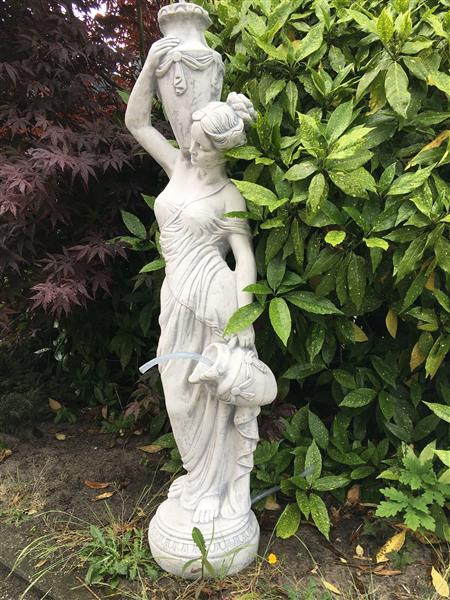 Grote foto prachtig wit stenen beeld van een staande dame met waterkruiken kan als fontein dienen bij de vijver tuin en terras tuindecoratie