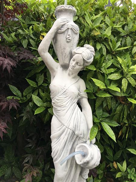 Grote foto prachtig wit stenen beeld van een staande dame met waterkruiken kan als fontein dienen bij de vijver tuin en terras tuindecoratie