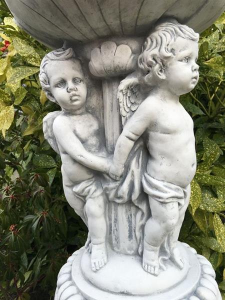 Grote foto prachtige zware bloempot vaas uit vol steen gedragen door engelen. tuin en terras tuindecoratie