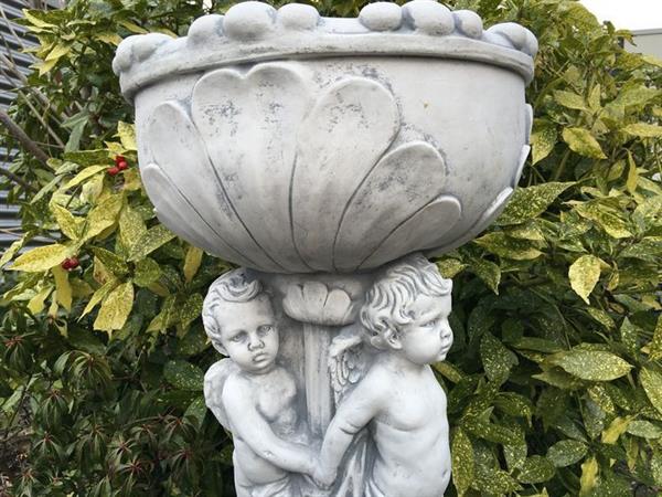 Grote foto prachtige zware bloempot vaas uit vol steen gedragen door engelen. tuin en terras tuindecoratie